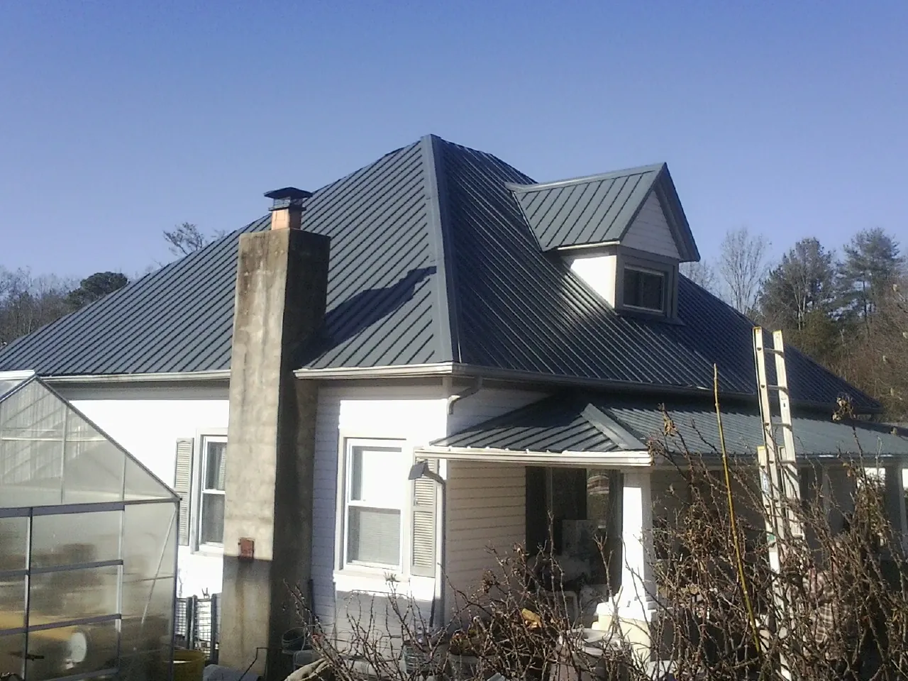 Dark blue standing seam metal roof on a white farmhouse with dormer — Slate & Tile Roof Repair by Roofing Brothers in Kennedale