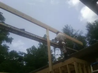 Carpenter setting a ridge beam over a new addition frame — Ice Dam Removal by Roofing Brothers in Kennedale