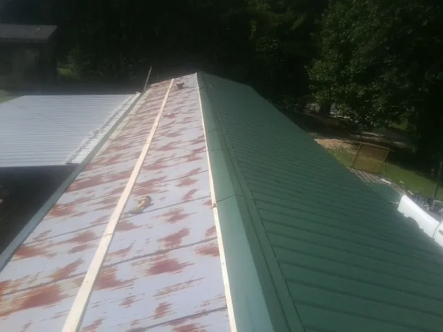 Old rusted panels beside newly installed green metal roofing — Wind Damage Roof Repair by Roofing Brothers in Kennedale
