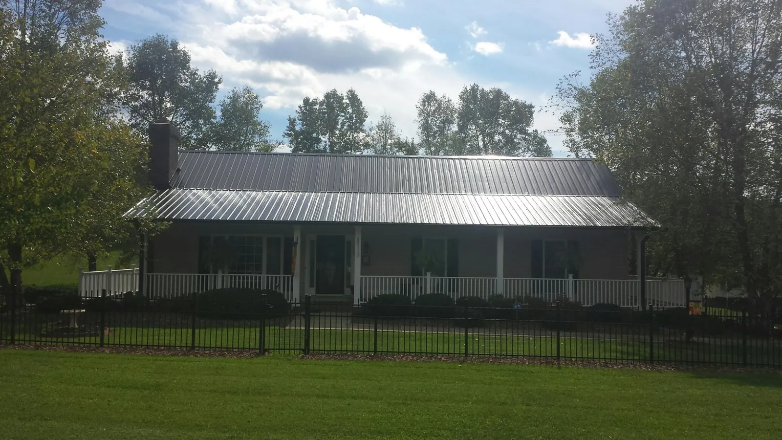Gray metal roof on a brick ranch with a full width front porch — Gutter Guard Installation work by our crew in Kennedale