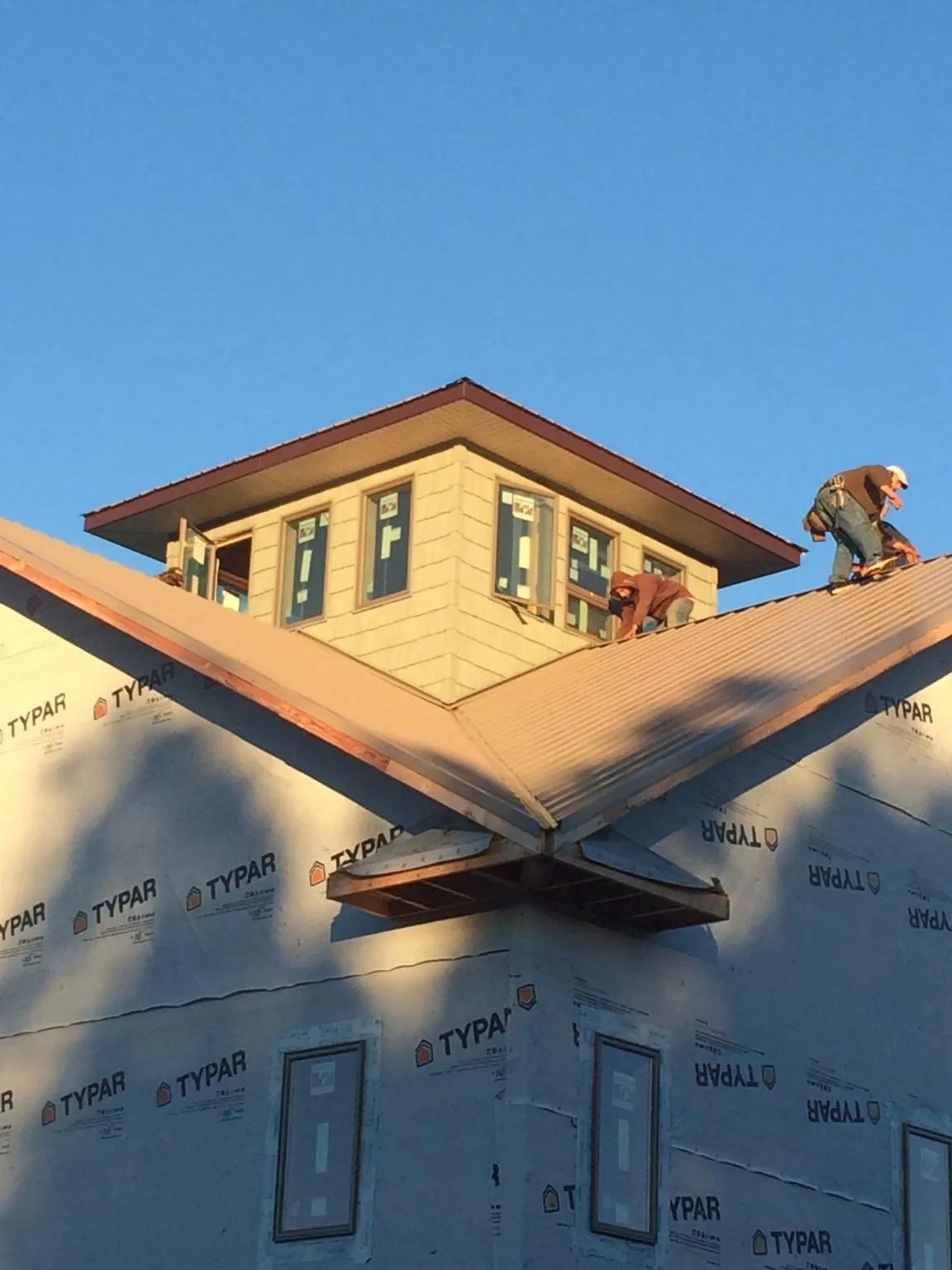Roofers working around a rooftop cupola on a new metal roof at sunset — Roof Waterproofing in Kennedale by Roofing Brothers